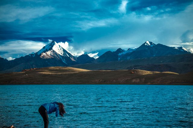 Woman Drinking Water from River with Majestic Mountains in Background - Download Free Stock Photos Pikwizard.com