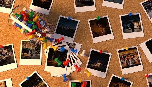 Spilling jar sending colorful push pins across corkboard with scattered polaroid prints