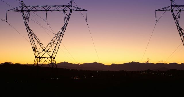 Silhouetted electrical towers with power lines extend across a scenic mountainous landscape during sunset. The orange and purple hues in the sky contrast against the dark outlines of the infrastructure and rolling hills. This image can be used to highlight themes related to energy, electricity infrastructure, nature, and the beauty of twilight in rural settings. Excellent for articles, environmental awareness materials, and landscape and industrial photography.