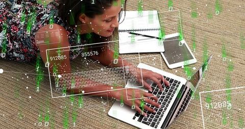 Young woman typing on laptop at home on rug with tablet and notebook, digital data overlay