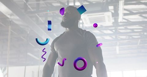 Backlit muscular athlete standing in industrial gym with neon 3d geometric overlays