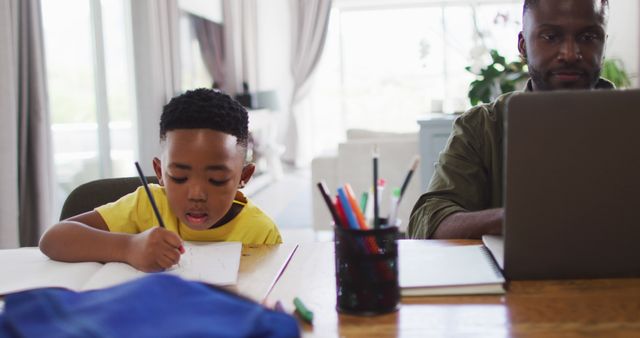 Father Working on Laptop While Son Doing Homework at Home - Download Free Stock Images Pikwizard.com