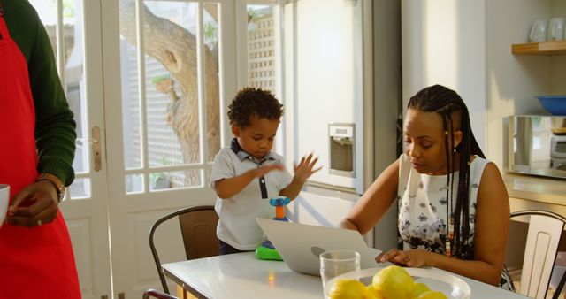 Busy African American Mother Working on Laptop While Child Plays Nearby - Download Free Stock Images Pikwizard.com