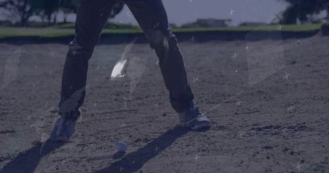 Golfer in bunker wearing jeans and sneakers preparing sand shot with golf ball overlays