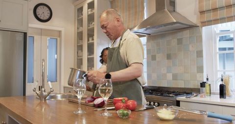 Senior man cooking in home kitchen with fresh vegetables
