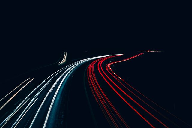 Capturing long exposure of moving car lights on urban highway at night. Ideal for use in automotive, transportation, travel, and urban scenes content. Great for backgrounds, websites, brochures, and articles exploring themes of motion, speed, and night cityscapes.