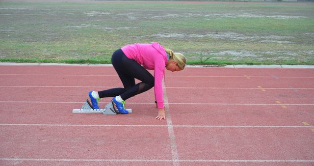 Female Runner in Pink Preparing for Sprint on Track - Download Free Stock Images Pikwizard.com