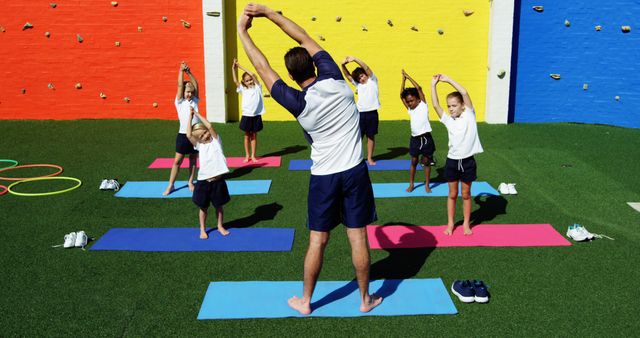 A male teacher guides children in an outdoor yoga stretch, emphasizing school wellness. - Download Free Stock Photos Pikwizard.com