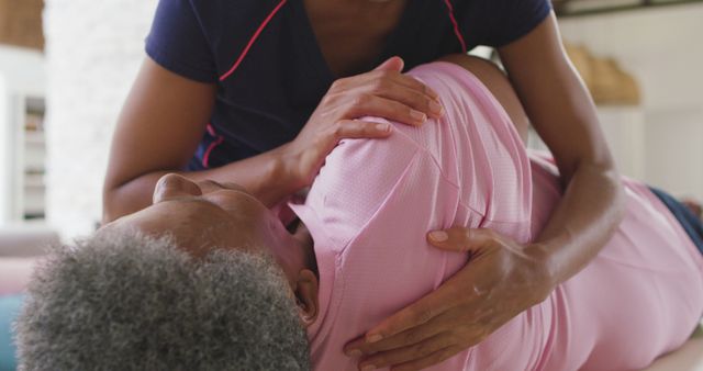 Elderly woman receiving assistance from a physiotherapist during therapy exercises indoors. Useful for illustrating healthcare services, home care support, physiotherapy, geriatric rehabilitation, and wellness for seniors.