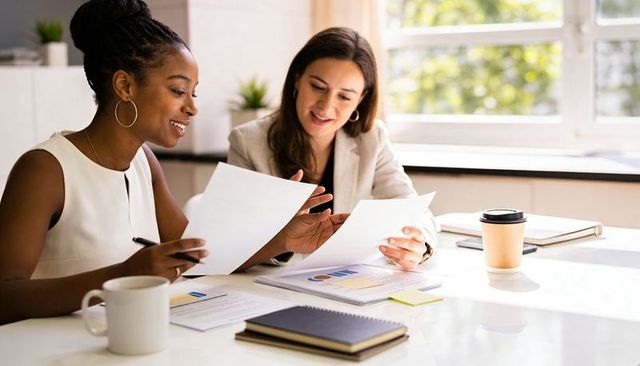 Two colleagues collaborating and reviewing charts in bright modern office meeting room
