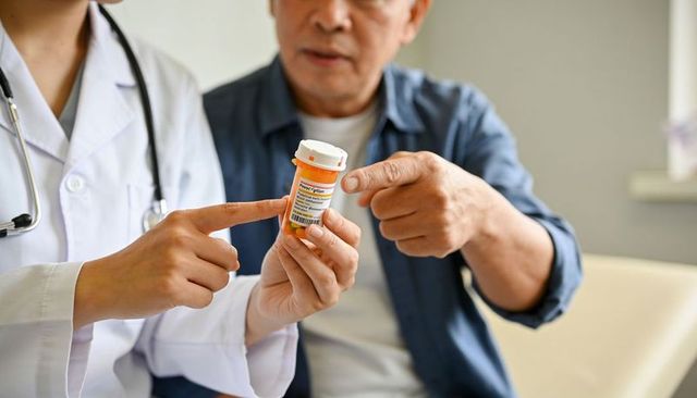 Doctor explaining prescription label to senior patient pointing at pill bottle for safety
