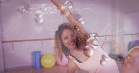 Curly-haired woman stretching at fitness studio with stability balls and tech overlay