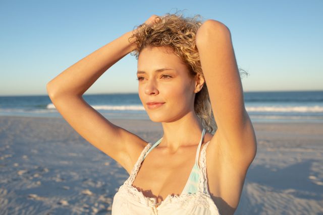 Woman standing with HANDS IN HAIR on the beach - Download Free Stock Photos Pikwizard.com