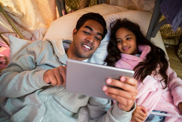 Father and daughter using digital tablet in the bedroom
