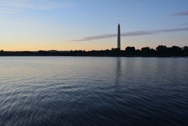 Sunset creates a serene atmosphere with the silhouette of the Washington Monument and reflections on the river, perfect for travel brochures, city guides, and tourism websites. Ideal for promoting Washington D.C. as a travel destination or for use in blogs and social media relating to scenic landmarks.