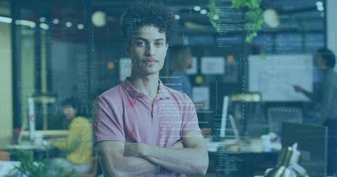 Young programmer standing confidently with arms crossed, futuristic coding hud in office