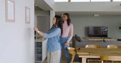 Friends hanging framed art in modern dining room