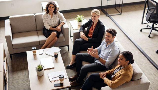 Collaborative team brainstorming in modern office lounge with coffee and open plan workspace