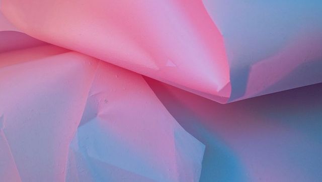 Crumpled pastel pink and blue sheets with water droplets