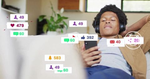 Young man relaxing on sofa streaming content and receiving social media notifications