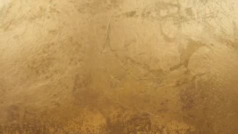 Shifting Ambient Light Revealing Gold Plaster Texture and Cracks in Slow Motion Loop