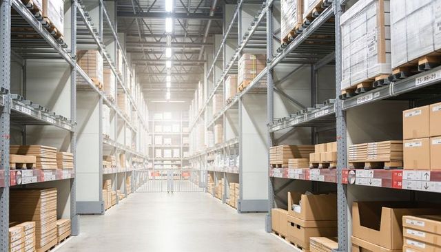 Bright high-bay warehouse aisle featuring organized pallet racks and stacked boxes