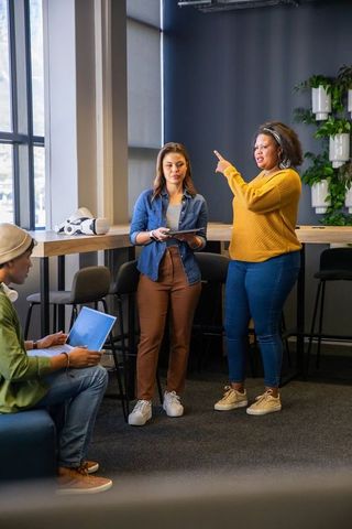 Diverse team collaborating in modern coworking lounge with tablet and VR headset