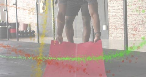 Unrolling red exercise mat by athletic man preparing workout in industrial gym