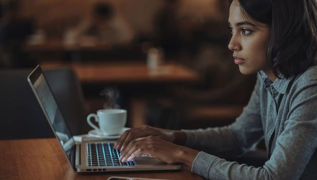 Typing on Laptop in Cozy Coffeeshop, Remote Work Freelancer Focused Young Woman