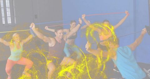 Group resistance band squats in studio with vibrant yellow powder motion
