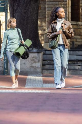 Diverse friends walking with yoga mat on sunny city sidewalk, casual urban lifestyle