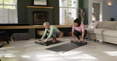 Diverse Women Unrolling Yoga Mats in Modern Living Room