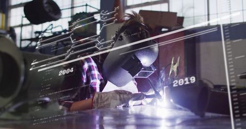 Woman Welder Operating TIG Torch in Industrial Workshop with HUD Code Overlay and Sparks