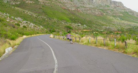 Skateboarder on Scenic Mountain Road with Expansive Landscape