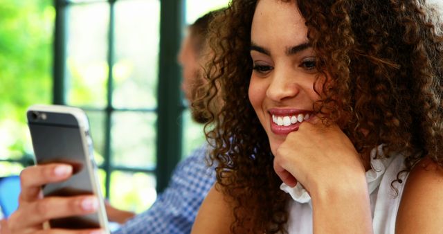 Smiling Woman Engaging with Smartphone in Bright Cafe - Download Free Stock Images Pikwizard.com