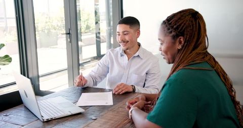 Team Meeting at Office Table with Laptop and Documents