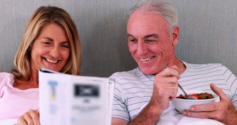 Happy Mature Couple Enjoying Breakfast in Bed Together