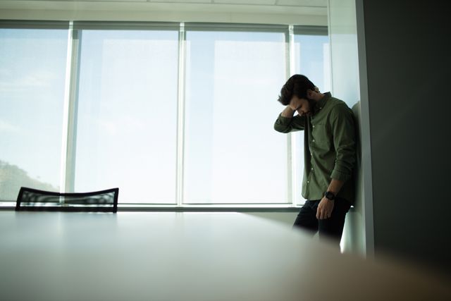 Depressed Businessman Standing by Office Window - Download Free Stock Photos Pikwizard.com