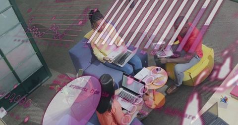 Collaborating in colorful breakout lounge with laptops and pink digital data overlay