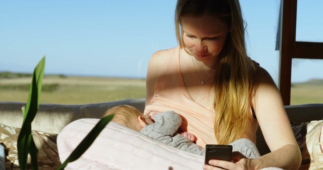 Mother Breastfeeding Baby While Using Smartphone in Sunlit Room - Download Free Stock Images Pikwizard.com