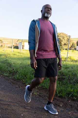 Senior man walking on path through green countryside