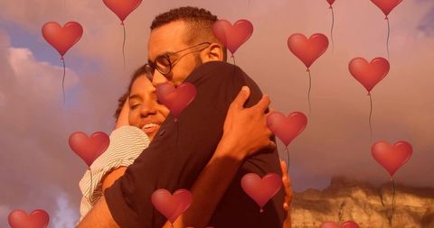 Couple embracing at golden hour with heart balloon overlay celebrating warm romance