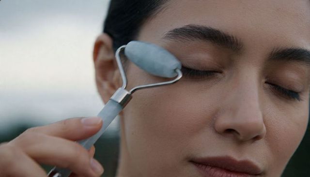 Closeup jade roller massaging eye for natural skincare de-puffing and gentle facial massage