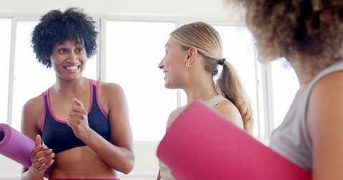 Diverse Women Conversing While Holding Yoga Mats in Studio