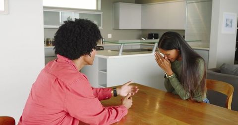 Diverse couple sharing emotional moment at home kitchen table