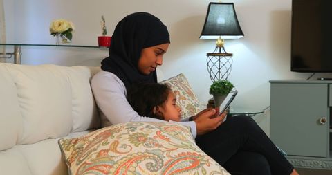 Asian Mother and Daughter Reading Digital Tablet at Home
