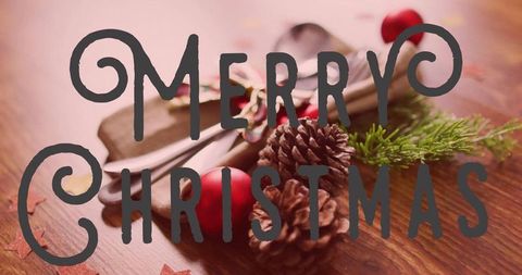 Rustic cozy merry christmas table decor with pinecones, red baubles and silverware closeup