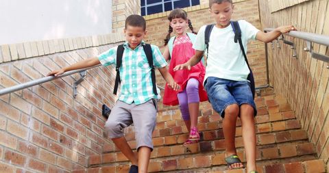Happy Schoolchildren Descending Brick Staircase Outdoors