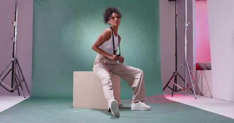 African american model posing on block wearing sneakers and suspenders studio portrait