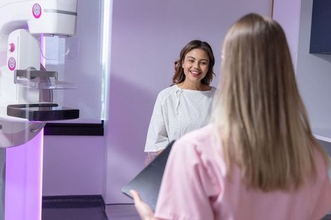 Patient visiting mammography clinic smiling during pre-scan consultation with technologist